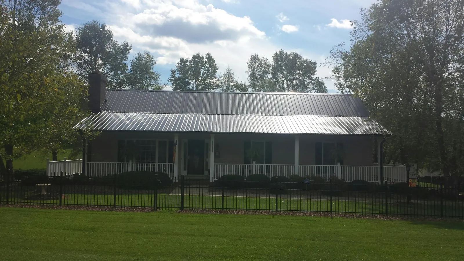 Gray metal roof on a brick ranch with a full width front porch — Gutter Guard Installation work by our crew in Lafayette