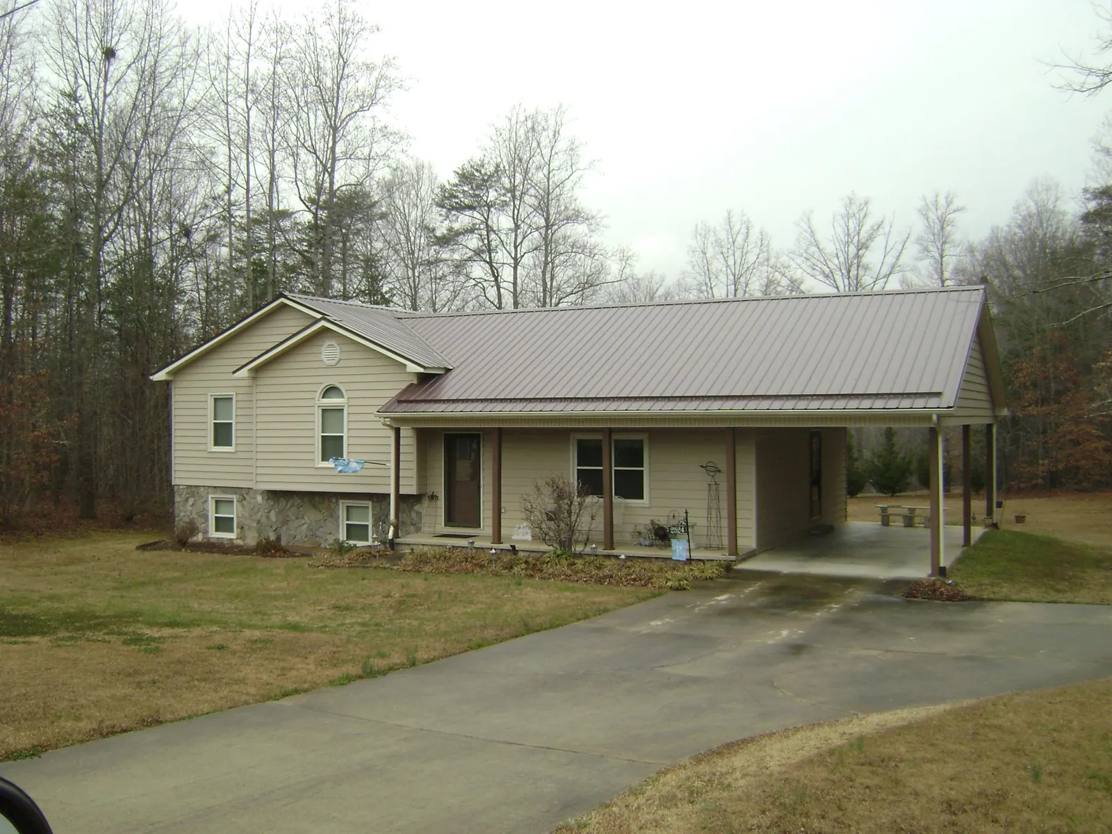 Brown metal roof on a tan split level home with an attached carport in Lafayette